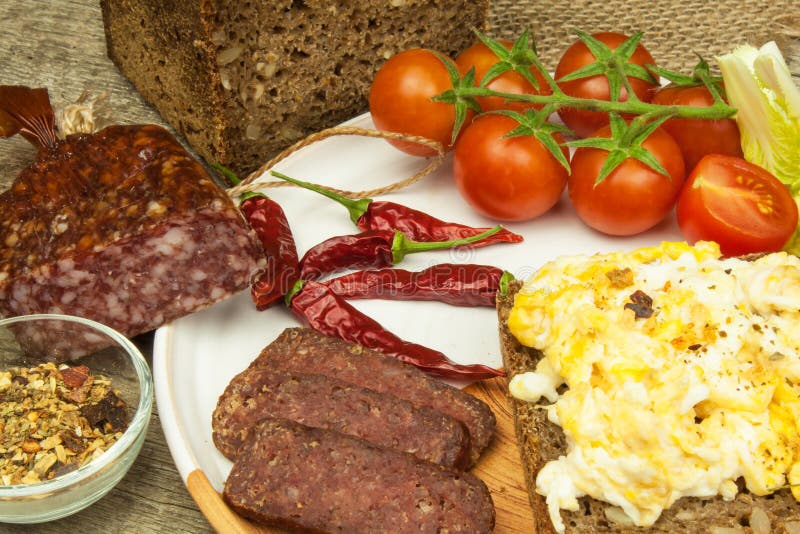 Scrambled Eggs with Bread and Salami. Egg Breakfast on a Wooden Table