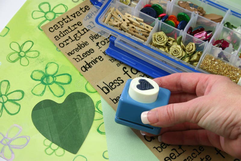 A selection of scrapbooking / craft materials with hand holding cutter. A selection of scrapbooking / craft materials with hand holding cutter