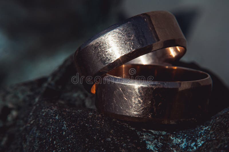 Scratched Two Wide Gold Wedding Rings on Stone Surface Stock Photo