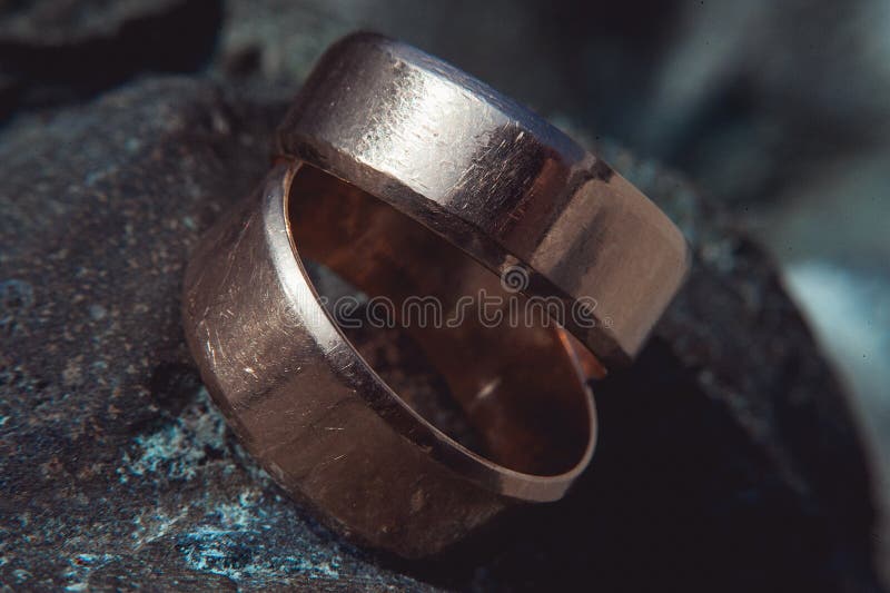 Scratched Two Wide Gold Wedding Rings on Stone Surface Stock Photo