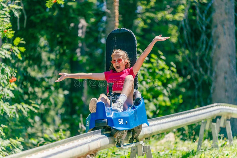 Screaming girl riding mountain roller coaster with outstretched arms