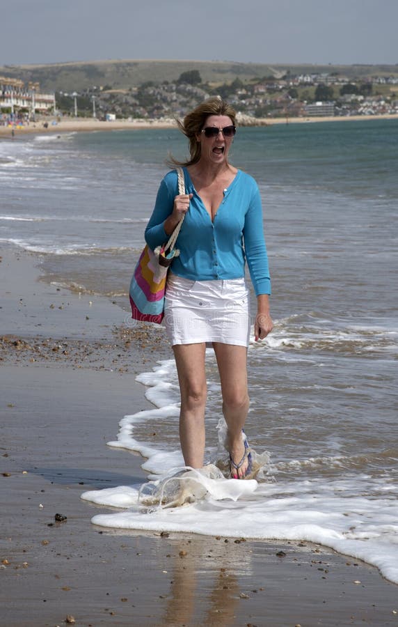 Cold water shock for woman walking along beach and standing in cold seawater. Cold water shock for woman walking along beach and standing in cold seawater