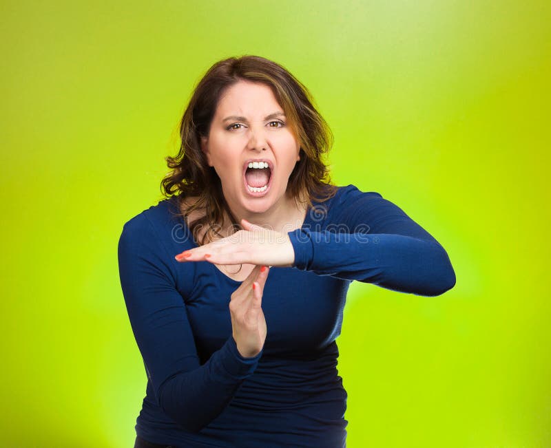 Closeup portrait middle aged screaming woman, showing time out gesture with hands, isolated green background. Negative human emotions, facial expressions, sign symbols, body language, attitude, reaction