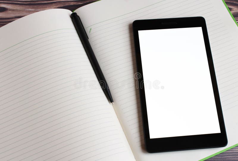 View from the side of a black laptop, which lies on the opened large notebook. In the center of the notebook is a black pen for wr