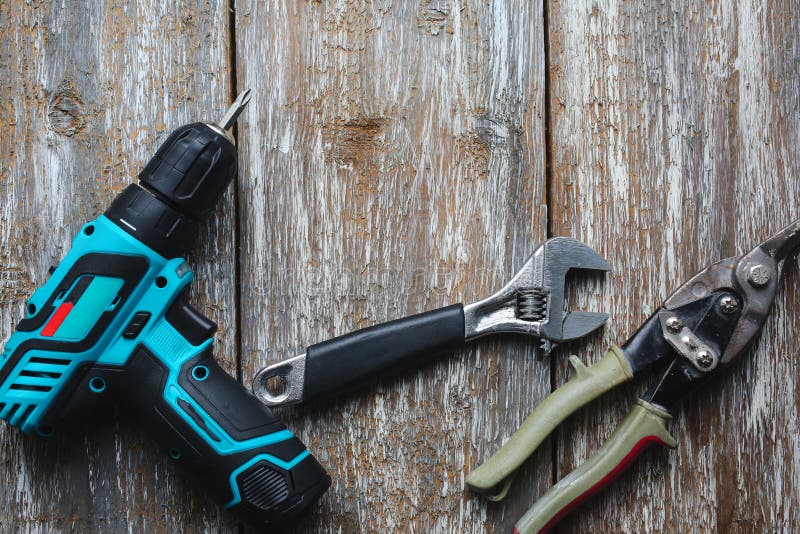 Screw gun, wrench, snips are lying on the old wooden background. Working instruments on the texture for maintenance repairing royalty free stock photo Screw gun, wrench, snips are lying on the old wooden background. Working instruments on the texture for maintenance repairing royalty free stock photo