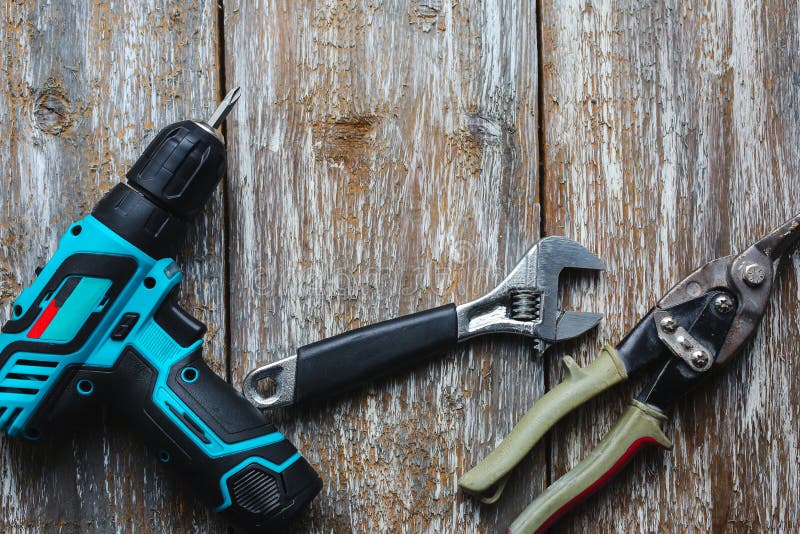 Screw gun, wrench, snips are lying on the old wooden background. Working instruments on the texture for maintenance repairing royalty free stock images Screw gun, wrench, snips are lying on the old wooden background. Working instruments on the texture for maintenance repairing royalty free stock images