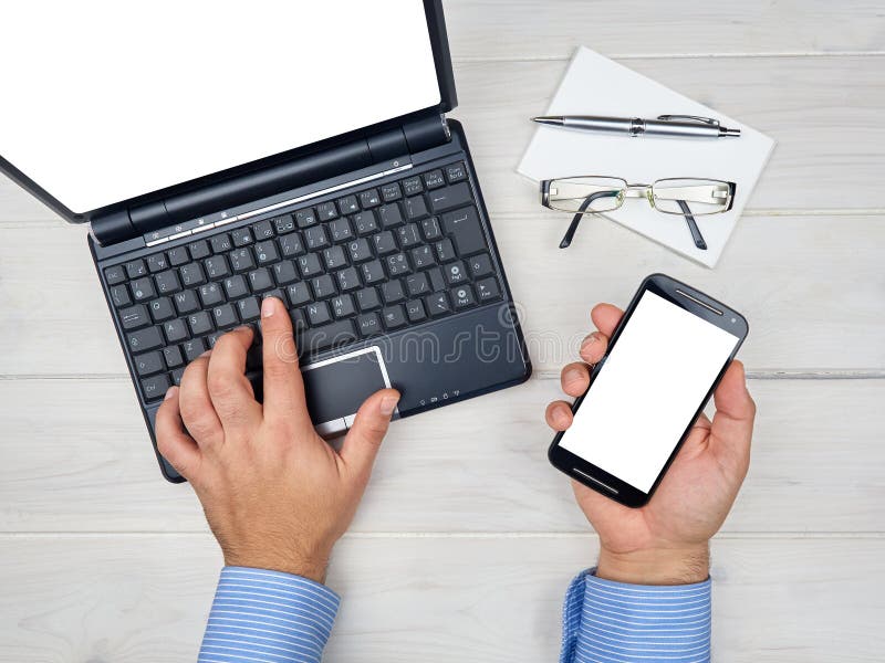 Scrittorio funzionante dell'uomo d'affari di vista superiore con lo smartphone del computer portatile immagine stock Scrittorio funzionante dell'uomo d'affari di vista superiore con lo smartphone del computer portatile immagine stock