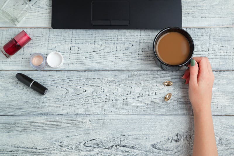 Scrivania posto di lavoro femminile mani, laptop, tazze di caffè, profumi e cosmetici da donna la vista dall'alto strato piatto fotografia stock libera da diritti Scrivania posto di lavoro femminile mani, laptop, tazze di caffè, profumi e cosmetici da donna la vista dall'alto strato piatto fotografia stock libera da diritti