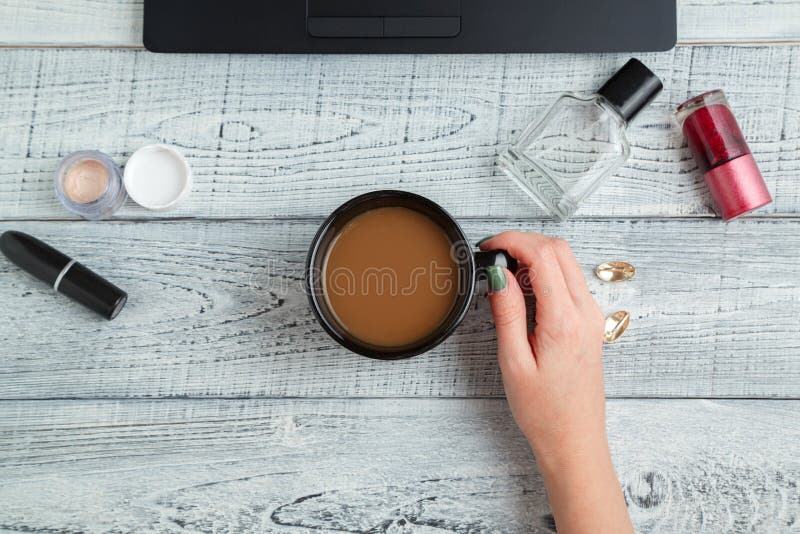 Scrivania posto di lavoro femminile mani, laptop, tazze di caffè, profumi e cosmetici da donna la vista dall'alto strato piatto immagini stock Scrivania posto di lavoro femminile mani, laptop, tazze di caffè, profumi e cosmetici da donna la vista dall'alto strato piatto immagini stock