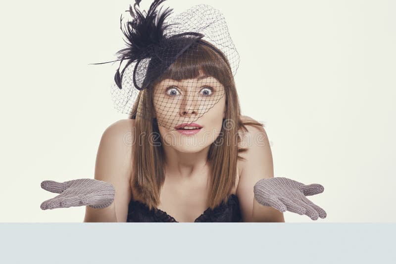 Pretty young woman shrugging her shoulders with clueless, questioning facial expression, wearing light feather hat, net and gloves, gesturing with open palms against bright background. Pretty young woman shrugging her shoulders with clueless, questioning facial expression, wearing light feather hat, net and gloves, gesturing with open palms against bright background