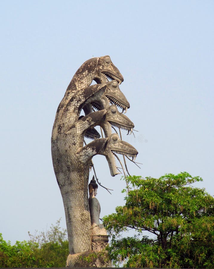 Mystical, unusulal mythological sculptures in Nong Khai Buddha Park in Thailand. Statues of Gods and magic creatures, snakes and people with lots of heads, hands and weapon in their arms in beautiful green park with bushes and flowers.