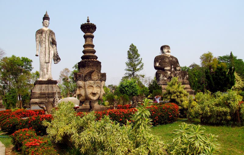 Mystical, unusulal mythological sculptures in Nong Khai Buddha Park in Thailand. Statues of Gods and magic creatures, snakes and people with lots of heads, hands and weapon in their arms in beautiful green park with bushes and flowers.