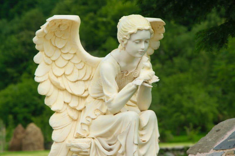 Scultura di marmo dell'angelo femminile che si siede sulla roccia e che tiene un uccello in sue mani immagini stock libere da diritti Scultura di marmo dell'angelo femminile che si siede sulla roccia e che tiene un uccello in sue mani immagini stock libere da diritti