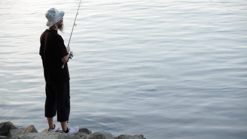 Se divierte la pesca del pescador en el río, usando señuelos de la pesca