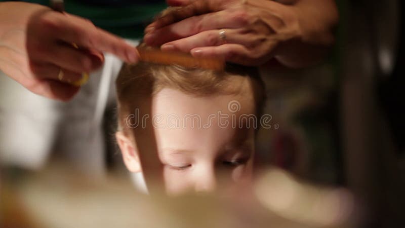 Se está cortando el pelo del niño pequeño.