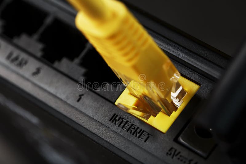 Se inserta un cable de conexión amarillo en el puerto wifi del router para acceder a internet imagenes de archivo