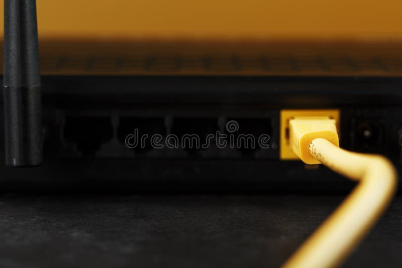 Se inserta un cable de conexión amarillo en el puerto wifi del router para acceder a internet fotografía de archivo libre de regalías