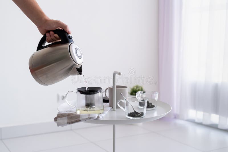 Se închide măsuța de cafea și se pune mâna pe om și se toarnă apă fierbinte pentru ceai royalty free stock photography