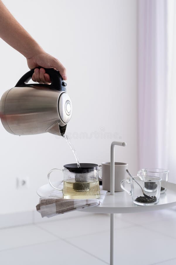 Se închide măsuța de cafea și se pune mâna pe om și se toarnă apă fierbinte pentru ceai stock photos