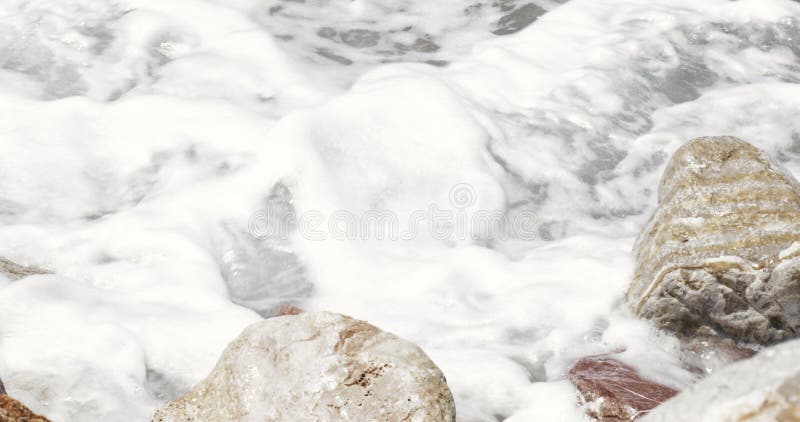 Sea abstract detail close-up rocks at the beach splashed by waves creating loads of sea foam â€“ Sea Abstract Background