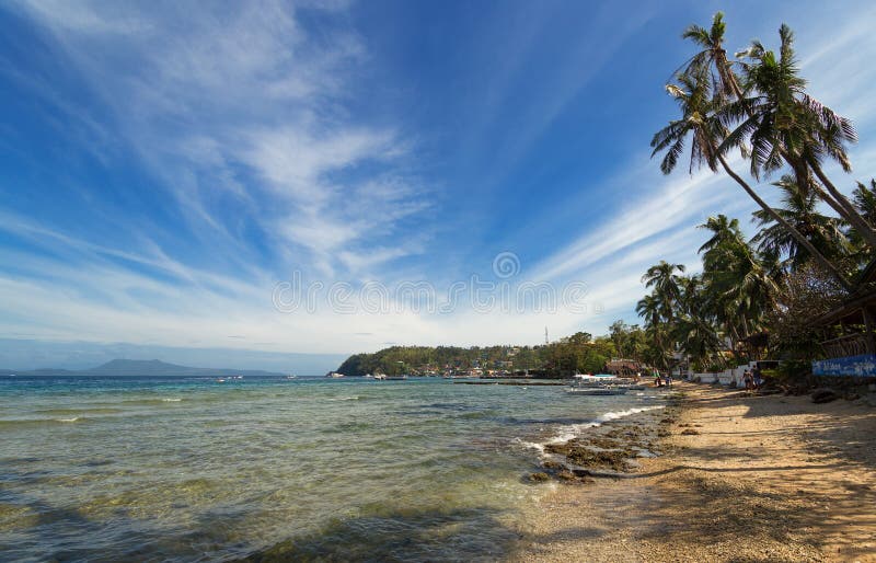 Sea, blue sky, palms and boats in White beach, Sabang, Puerto Galera, Philippines. Popular tourist and diving spot