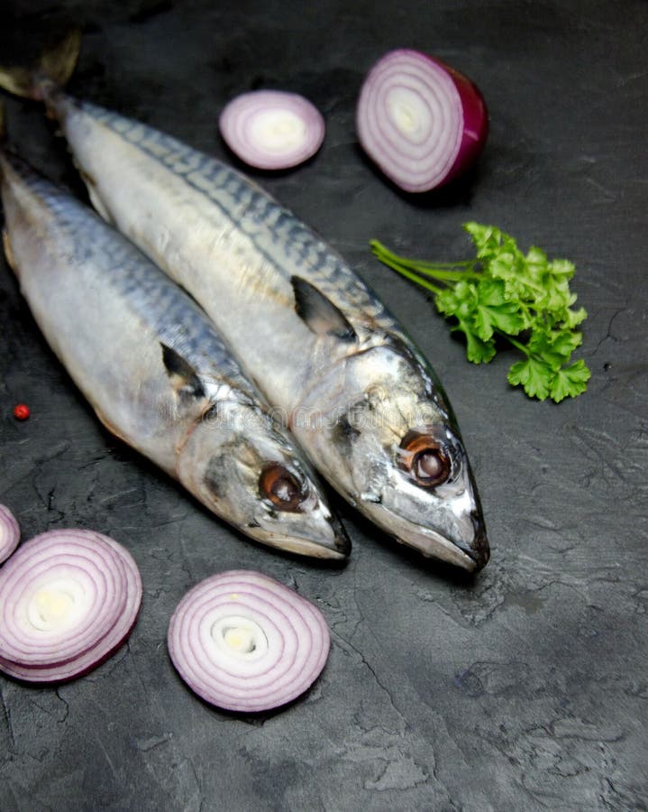 Sea Fish Raw Mackerel and Onion and Spices on a Black Table Selective