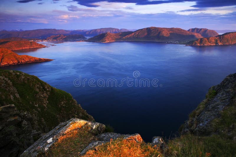 Sea landscape in the Norway. Evenig pink light on the ocean coast. Rocky cost in the summer night. Water surface with beautiful light.