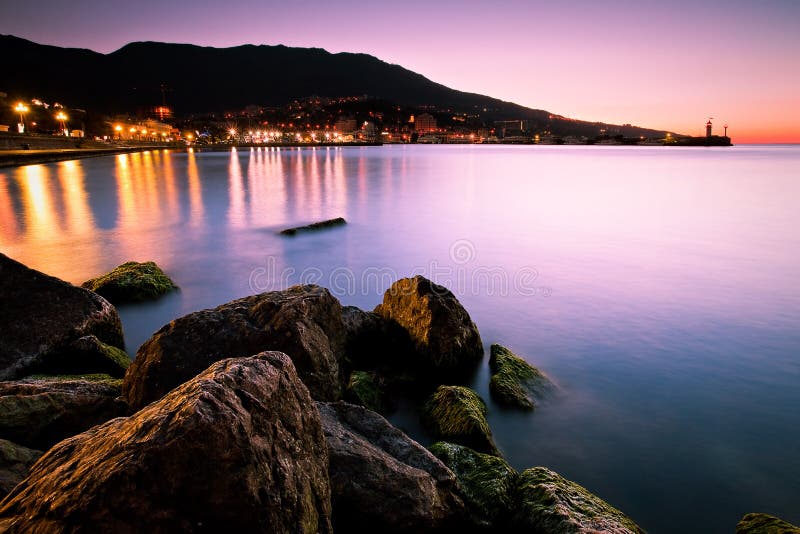 Sea landscape during sunrise with city lights