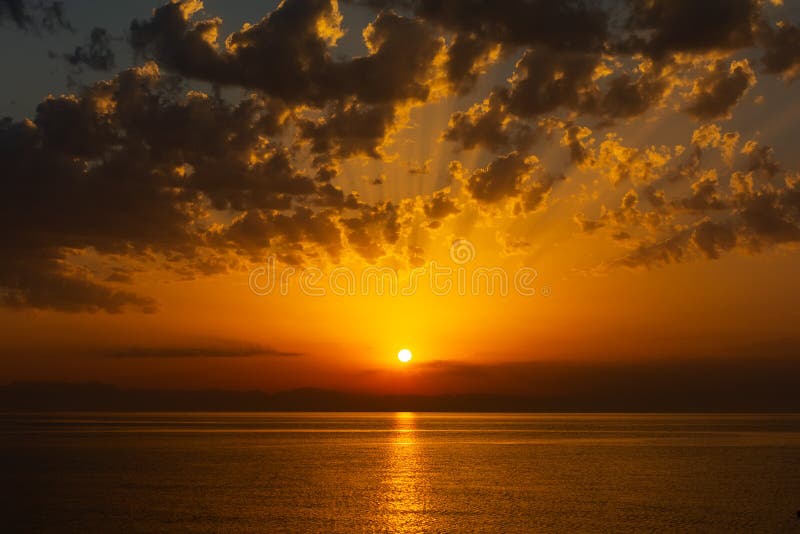 Sea landscape with sunrise, mountains and cloudy sky