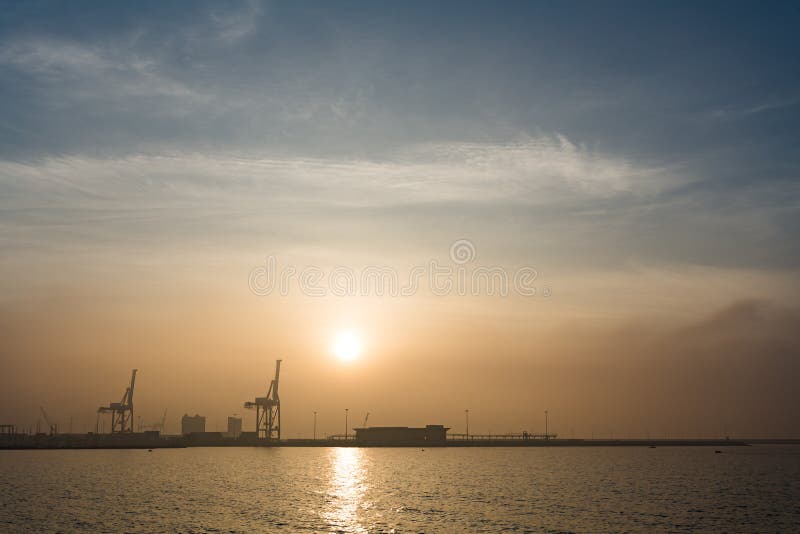 Sea port with crane and sunrise or sunset