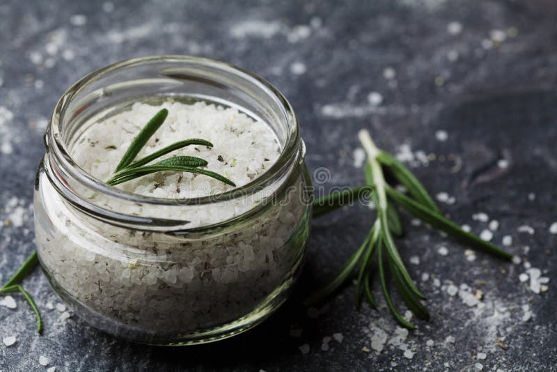 Sea salt scented herb rosemary on black stone background. Granular, condiments.