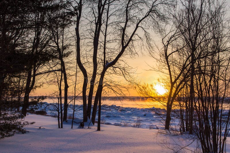 Sea smoke rising over the St. Lawrence River seen from the north shore during a beautiful winter sunrise stock images Sea smoke rising over the St. Lawrence River seen from the north shore during a beautiful winter sunrise stock images