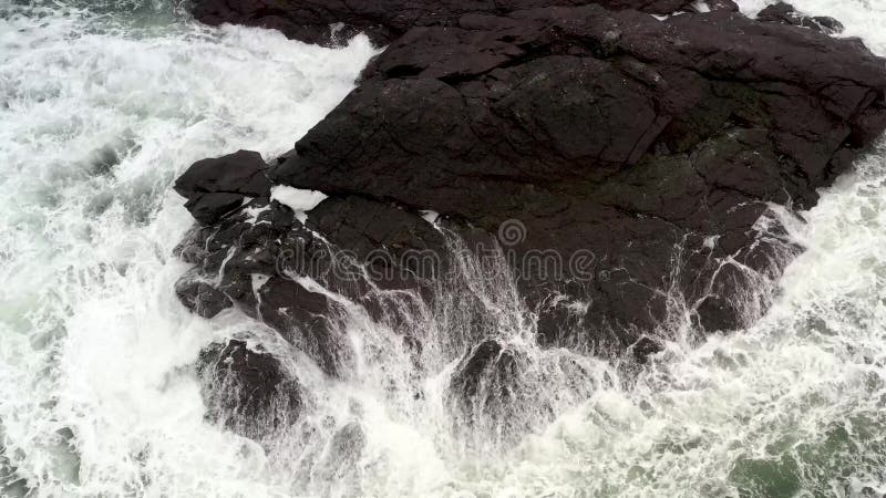 The sea wave runs on the black rock breaking into splashes stock video