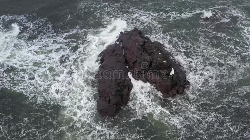 The sea wave runs on the black rock breaking into splashes. stock video