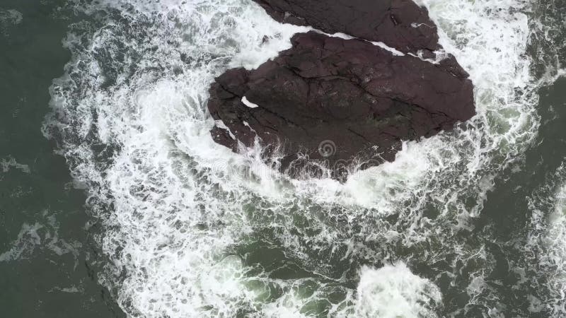The sea wave runs on the black rock breaking into splashes. stock video