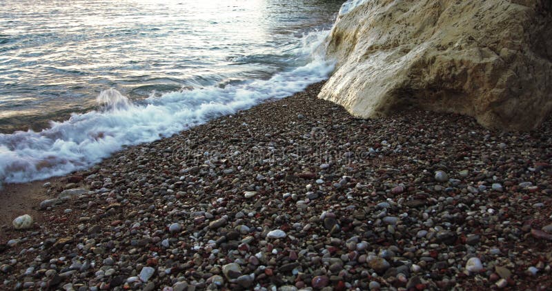 Sea waves hitting the white rock on a beach with sand, stones and pebbles slow motion â€“ Seascape Backgrounds