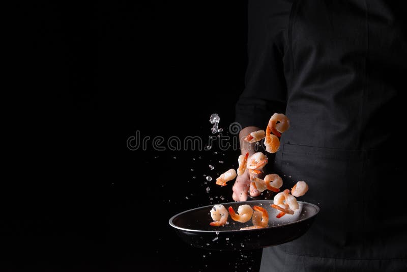 Seafood, chef prepares shrimps in a frying pan, roasts. On a black background for design, menus, restaurants, oriental cuisine, .