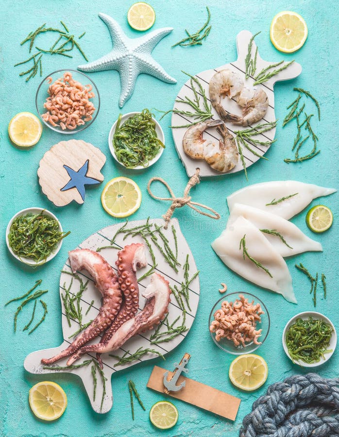 Seafood concept. Various seafood on light blue background, decorated with seaweeds , top view