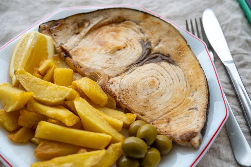 Seafood dish, grilled steak from swordfish or spada served with french fried potatoes and green olives