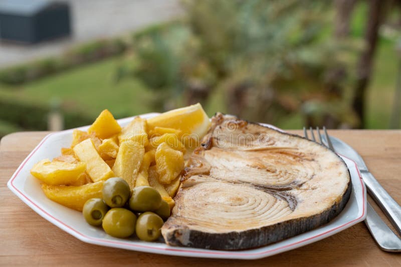 Seafood dish served in beach cafe with sea view, grilled steak from swordfish or spada served with french fried potatoes and green