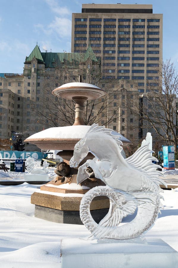 Ice sculpture in Ottawa, on a sunny day with city buildings behind. Ice scupltrure is of a seahorse creature, with horse head and fish or mermaid tail. Ice sculpture in Ottawa, on a sunny day with city buildings behind. Ice scupltrure is of a seahorse creature, with horse head and fish or mermaid tail.