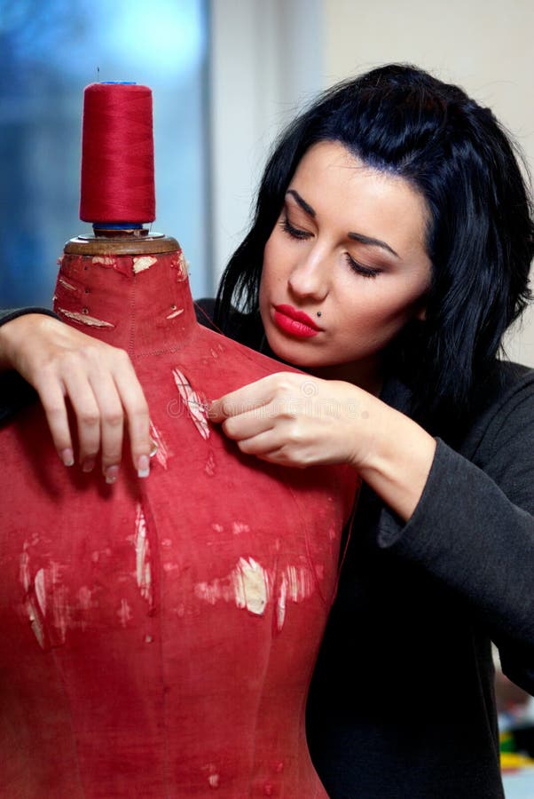 Seamstress repairs red old mannequin