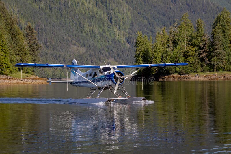 Seaplane landing in a remote cove near Ketchikan, Alaska. Calm water and beautiful tree lined mountains in the background