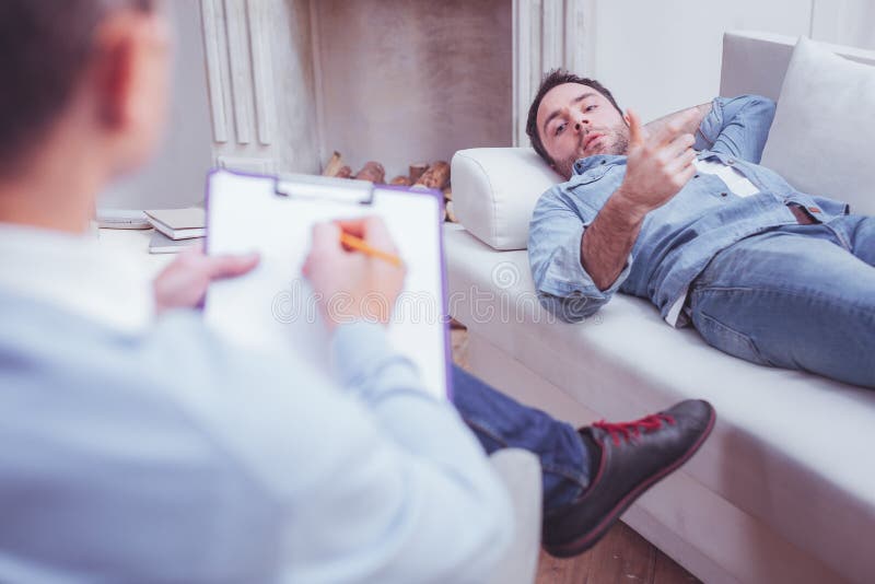 Downhearted bearded man attending psychologist