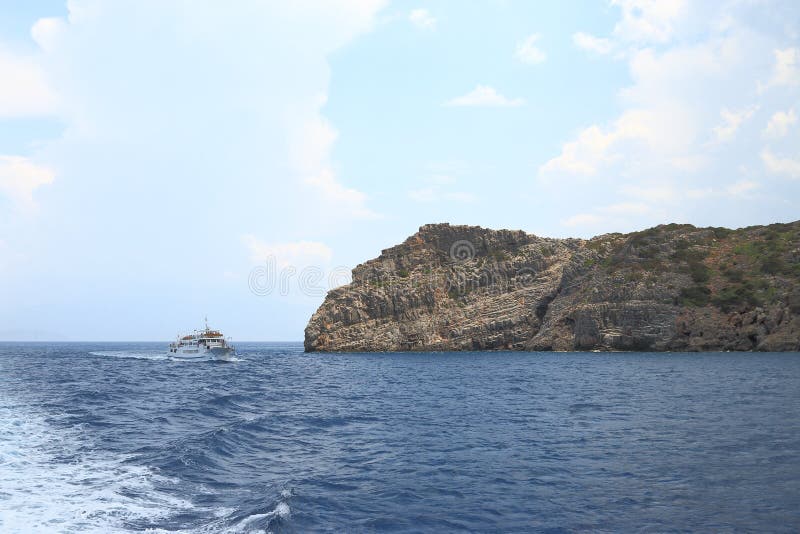 Seascape. Przyjemności łódź z turystami na pokładzie rusza się blisko skalistego brzegowego Crete, Grecja