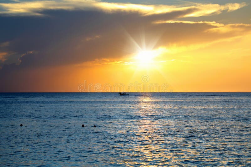 seascape image with shiny sea and speedboat over cloudy sky and sun during sunset in Cozumel, Mexico