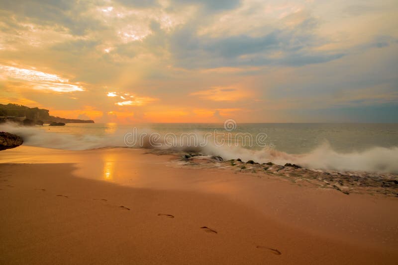 Seascape. Sunset time at the beach. Beach background with footprints in the sand. Tegal Wangi beach, Bali, Indonesia