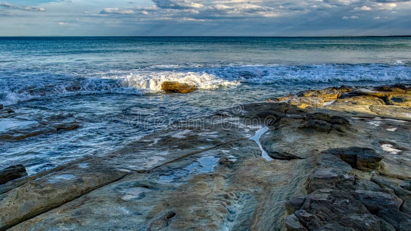 Seascape z ampuła głazami w wody morskiej niebie z chmurami przed podeszczowym szerokim wizerunkiem i skałami zdjęcia royalty free