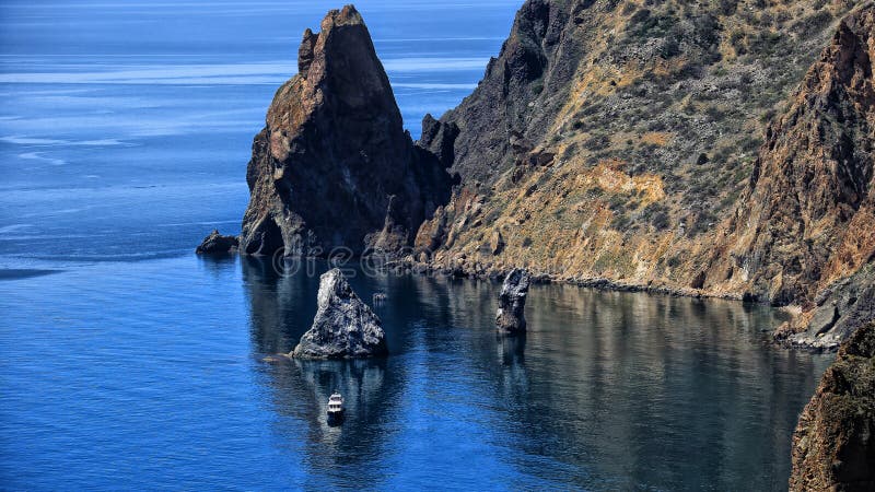 Seascape βουνά και βράχοι ένα μόνο σκάφος στο νερό στοκ φωτογραφίες με δικαίωμα ελεύθερης χρήσης Seascape βουνά και βράχοι ένα μόνο σκάφος στο νερό στοκ φωτογραφίες με δικαίωμα ελεύθερης χρήσης