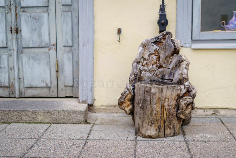 Seat made with a wooden log next to an old door and a medieval house.